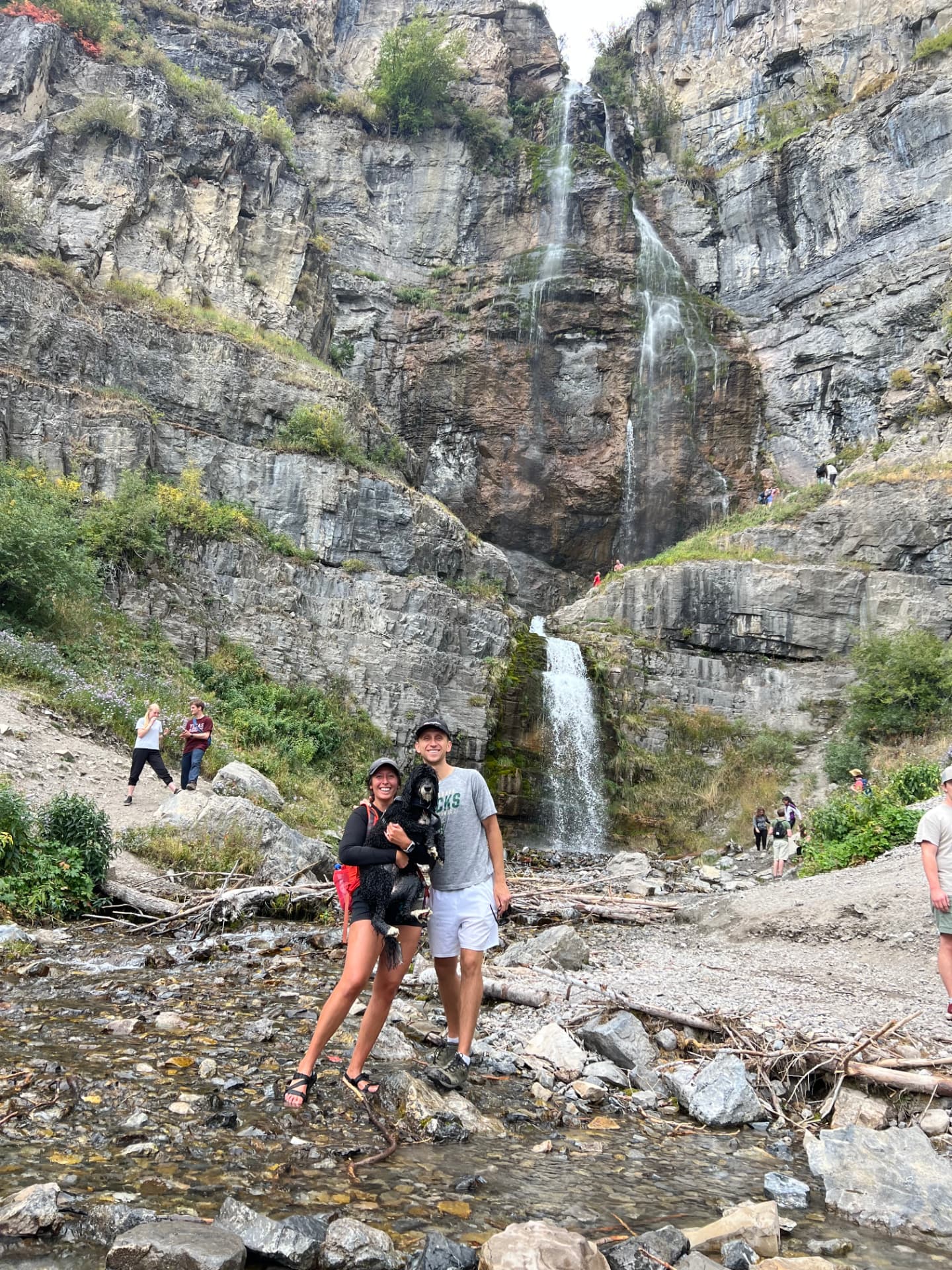 Melanie and family with their dog at a waterfall in the mountains